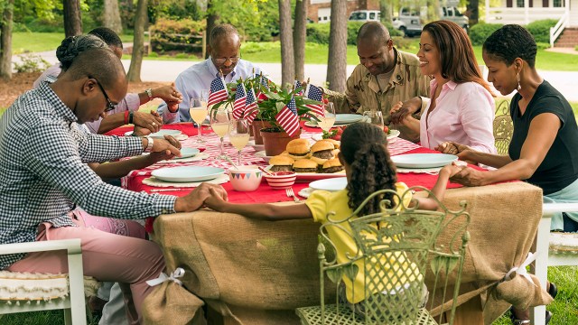 A multi-generation Black family prays at a picnic table. (Mark Edward Atkinson/Tracey Lee via Getty Images)