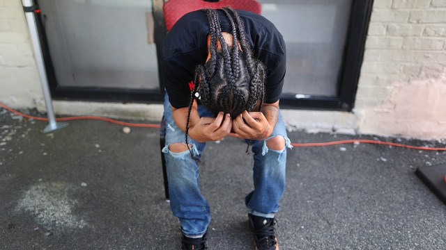 A person bows her head in her hands at a COVID-19 testing site in Boston on July 15, 2020. (John Tlumacki/The Boston Globe via Getty Images)