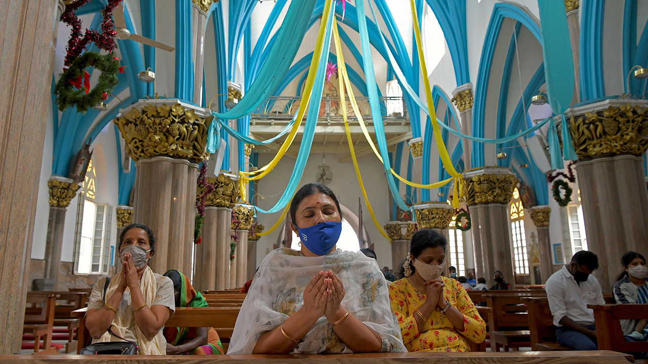 křesťanští oddaní, kteří nosí obličejové masky, se modlí v bazilice Panny Marie v Bengaluru v prosinci. 24, 2020. (Manjunath Kiran/AFP přes Getty Images)