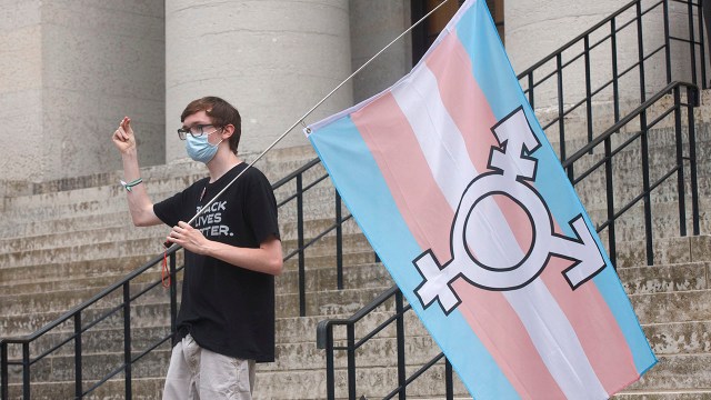 A protester holds the trans flag and snaps in solidarity with other transgender rights advocates during a demonstration outside the Ohio Statehouse on June 6, 2021.