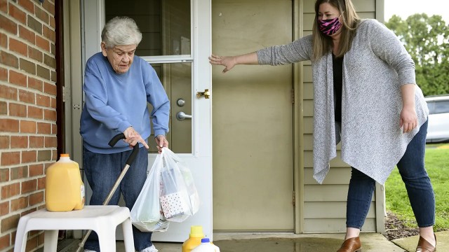 Shannon Flemming delivers groceries to Joyce Herzog in Kurtztown, Pennsylvania, on April 8 as part of a community effort to allow seniors to stay at home during the COVID-19 outbreak. (Lauren A. Little/MediaNews Group/Reading Eagle via Getty Images)