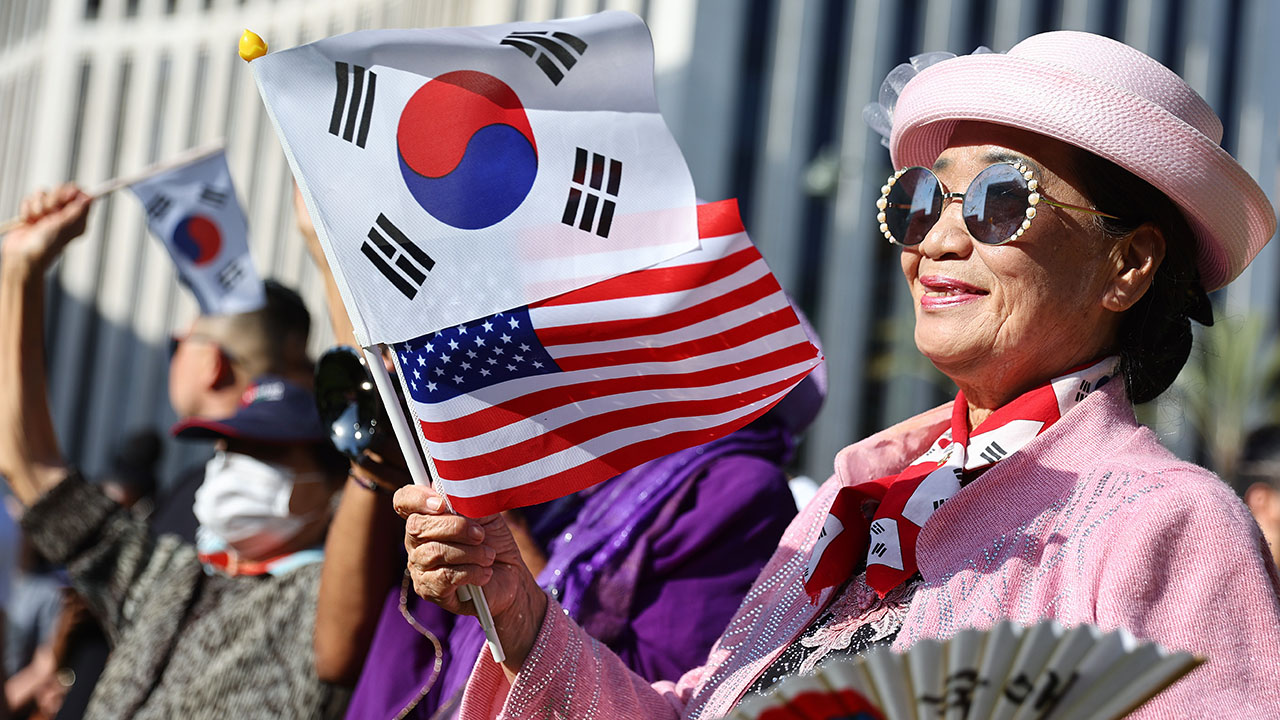 A woman waves Korean and American flags at an event in Los Angeles' Koreatown neighborhood in April 2022. (Mario Tama/Getty Images)