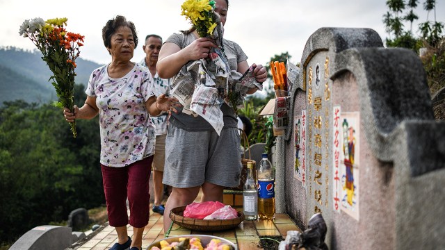 A Chinese Malaysian family lays flower offerings at their ancestor's grave during the annual Qingming Festival (also known as Tomb Sweeping Day) in Karak, Malaysia. (Mohd Rasfan/AFP via Getty Images)