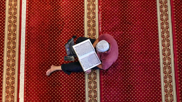 A man reads the Quran after praying at a mosque in Banda Aceh, Indonesia. (Chaideer Mahyuddin/AFP via Getty Images)