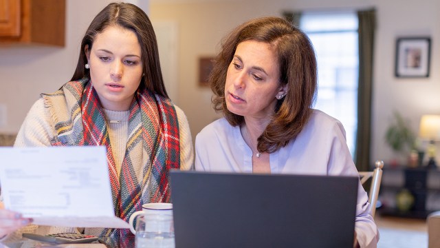 Mother and daughter at home reconciling bank statements