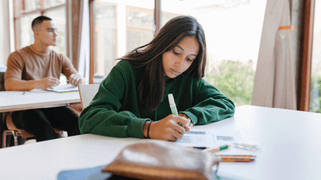 A high school student sitting at her desk concentrating during a test in class.